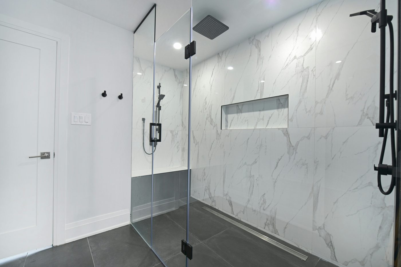 Glass-enclosed shower with marble walls